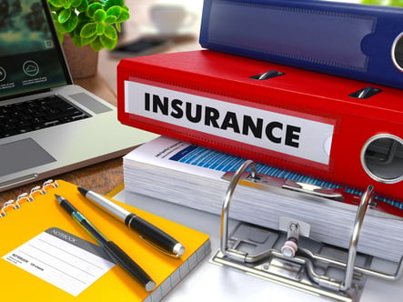 Red Ring Binder with Inscription Insurance on Background of Working Table with Office Supplies, Laptop, Reports. Toned Illustration. Business Concept on Blurred Background.-1